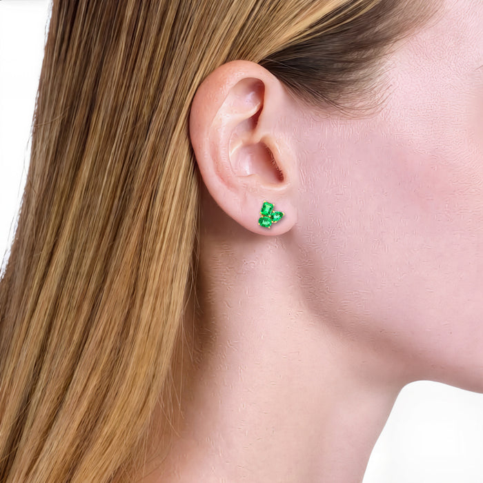 Three-Stone Vivid Colombian Emerald Stud Earrings (1 ¾ ct. tw.) in 18k Yellow Gold shown on the ear (light skin tone)