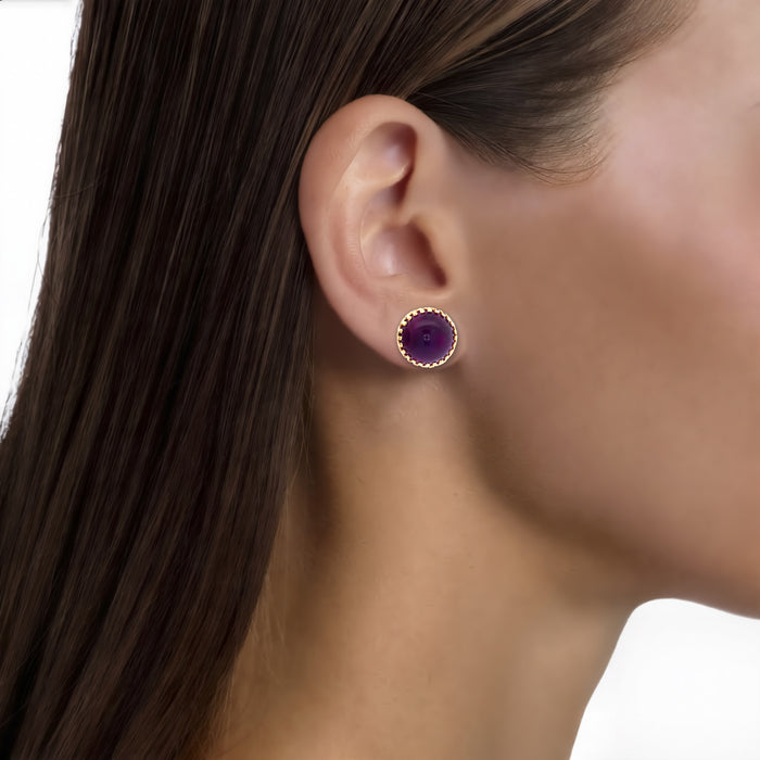 Deep Amethyst Cabochon Stud Earrings (16 ½ ct. tw.) in 14k Yellow Gold shown on the ear (medium skin tone)