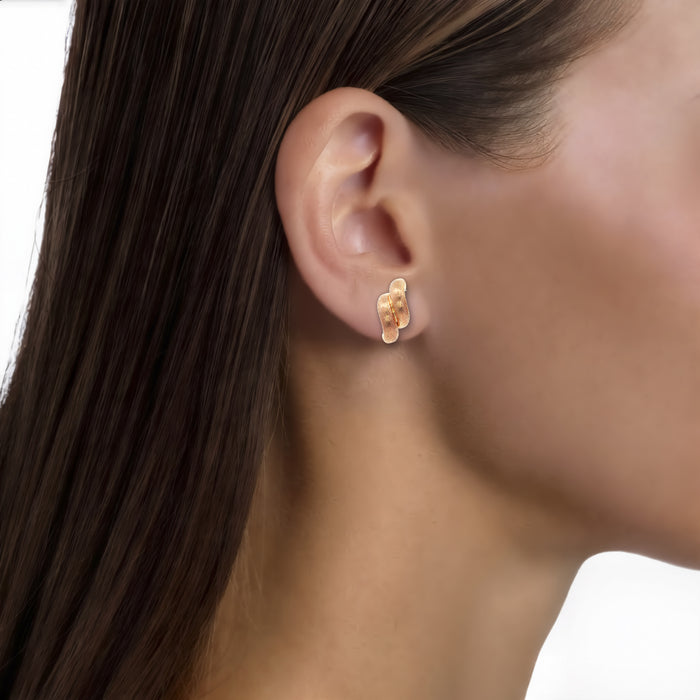 Dual Swirl Textured Stud Earrings in 14k Rose Gold shown on the ear (medium skin tone)