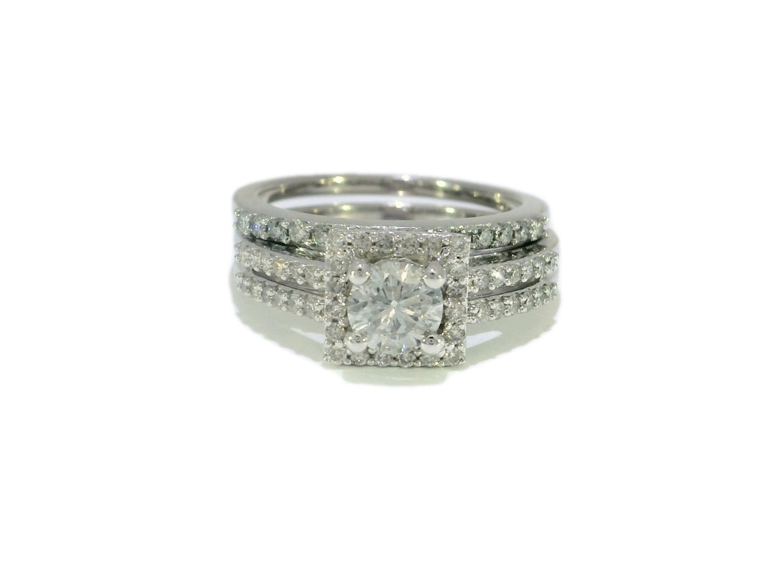 A bridal set featuring a round brilliant cut diamond halo engagement ring with a double-row diamond-studded band, complemented by a matching wedding band, all in 14KT white gold.