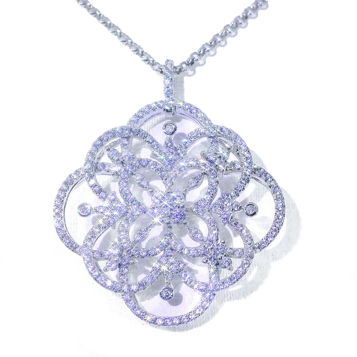 A large, intricate snowflake-shaped pendant necklace in white gold with small diamond-like accents throughout.