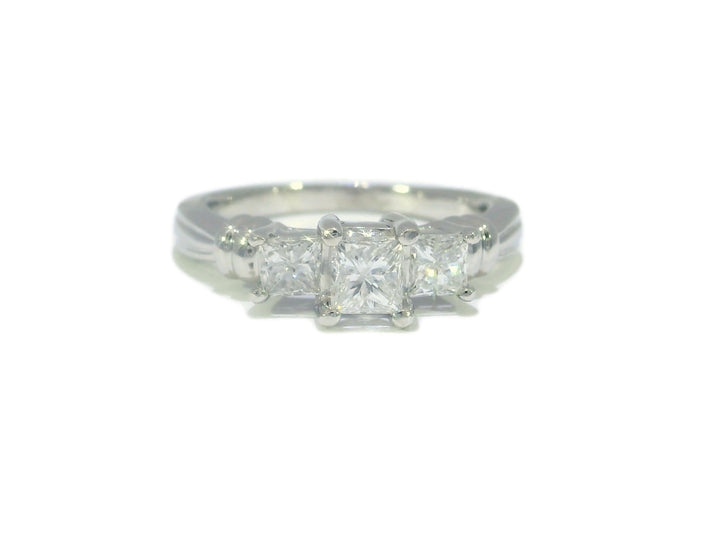 A colorless three-stone diamond engagement ring with a princess-cut center stone and two matching side stones, set in platinum.