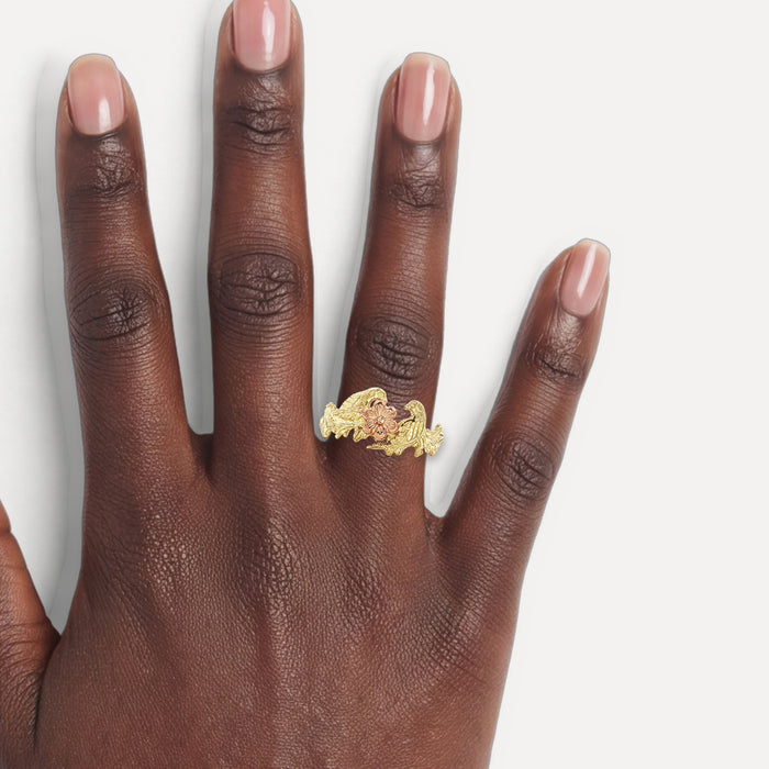 Vintage Black Hills Gold Grape Leaf & Bird Ring in 14k Two-Tone Yellow and Rose Gold shown on a hand (deep skin tone)