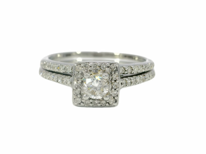 A radiant cut diamond engagement ring with a halo of smaller diamonds, set in a white gold band, accompanied by a matching band.