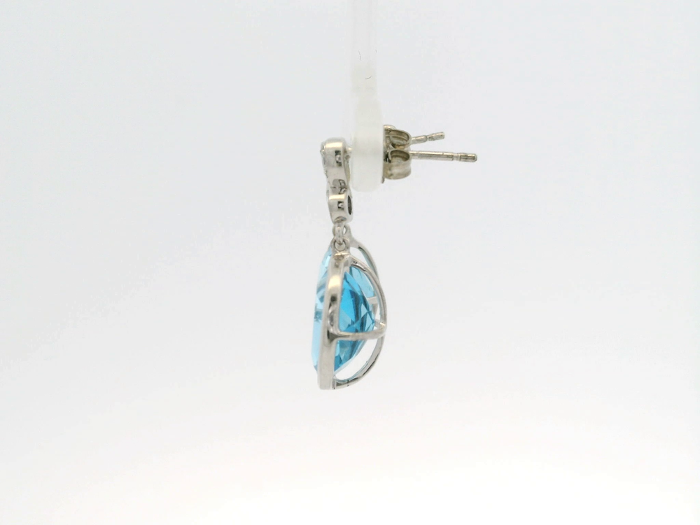 Silver earring with oval blue gemstone in a prong setting, fine jewelry photo