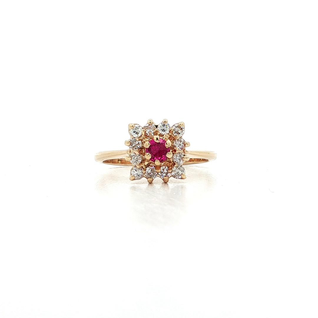 Gold ring with a central red gemstone and diamond halo on a white background