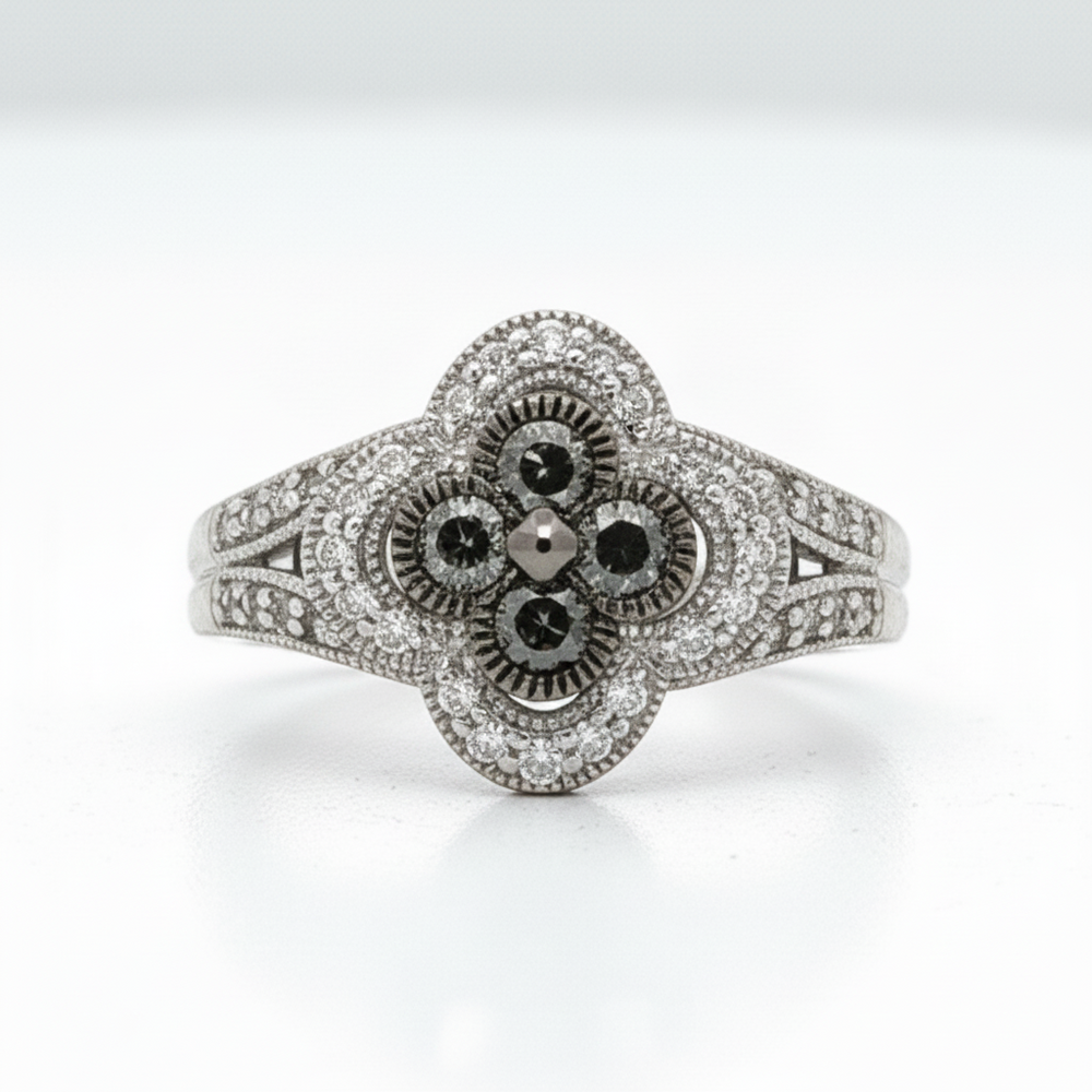 A silver-toned Art Deco style ring featuring a four-petal floral design with dark center stones and pavé-set accents, shown on a plain white background.