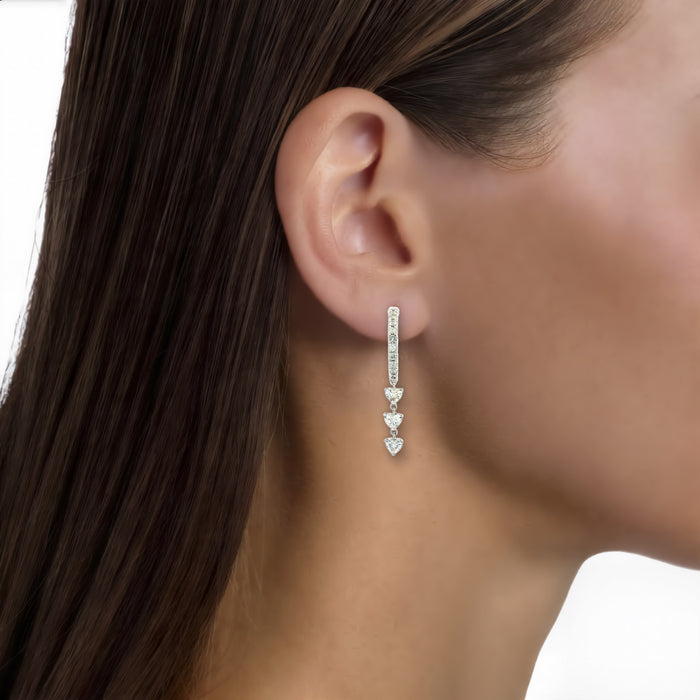 Heart Colorless Nearly Flawless Diamond Dangle Hoop Earrings (⅞ ct. tw.) in 18k White Gold shown on the ear (medium skin tone)