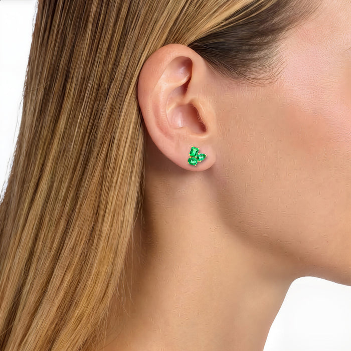 Three-Stone Vivid Colombian Emerald Stud Earrings (1 ¾ ct. tw.) in 18k Yellow Gold shown on the ear (light medium skin tone)