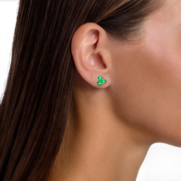Three-Stone Vivid Colombian Emerald Stud Earrings (1 ¾ ct. tw.) in 18k Yellow Gold shown on the ear (medium skin tone)