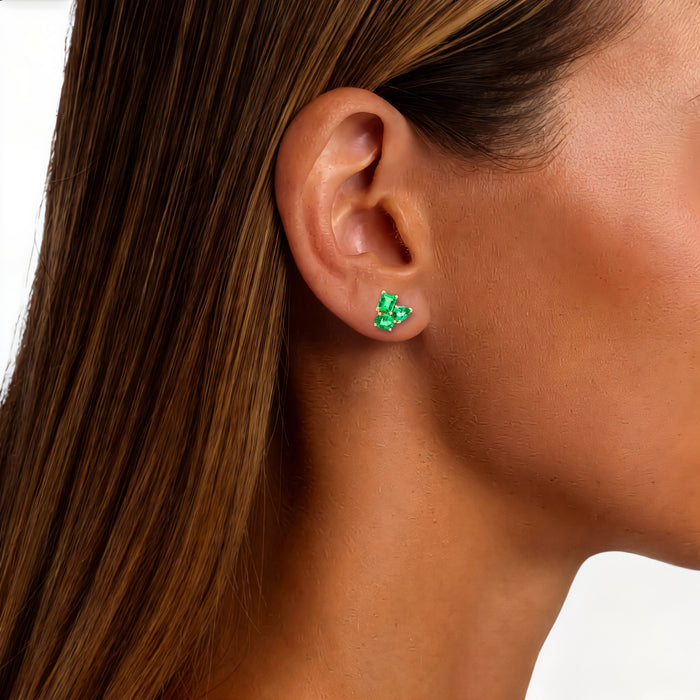 Three-Stone Vivid Colombian Emerald Stud Earrings (1 ¾ ct. tw.) in 18k Yellow Gold shown on the ear (medium deep skin tone)