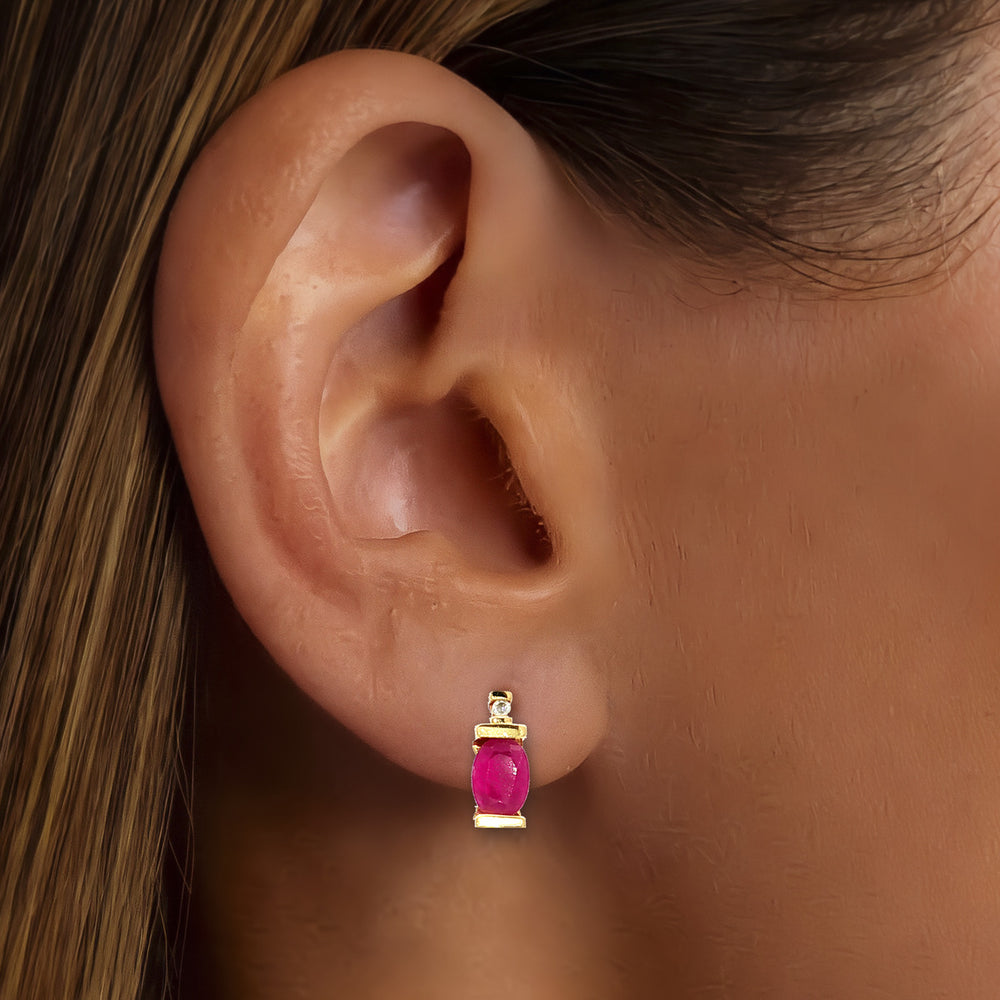Oval-Shaped Ruby & Diamond Stud Earrings (⅞ ct. tw.) in 10k Yellow Gold shown on the ear (medium deep skin tone)