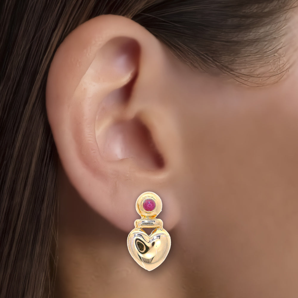 Cabochon Ruby Heart-Shaped Stud Earrings (½ ct. tw.) in 14k Yellow Gold shown on the ear (medium skin tone)