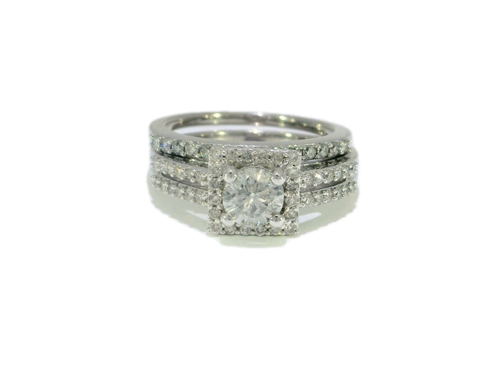 A bridal set featuring a round brilliant cut diamond halo engagement ring with a double-row diamond-studded band, complemented by a matching wedding band, all in 14KT white gold.