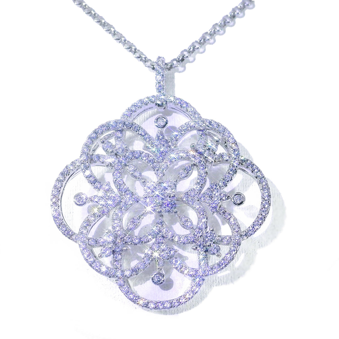 A large, intricate snowflake-shaped pendant necklace in white gold with small diamond-like accents throughout.