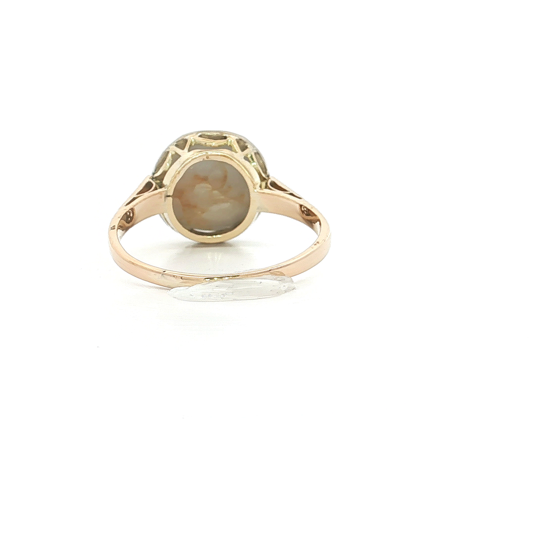 Vintage-style gold ring with an oval cameo setting, displayed on a white background.