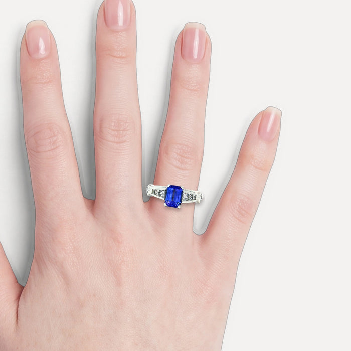 Vivid Emerald-Cut Tanzanite Channel-Set Diamond Ring (2 ¼ ct. tw.) in 18k White Gold shown on a hand (light skin tone)