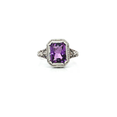 Vintage-style silver ring with emerald-cut purple gemstone and filigree band