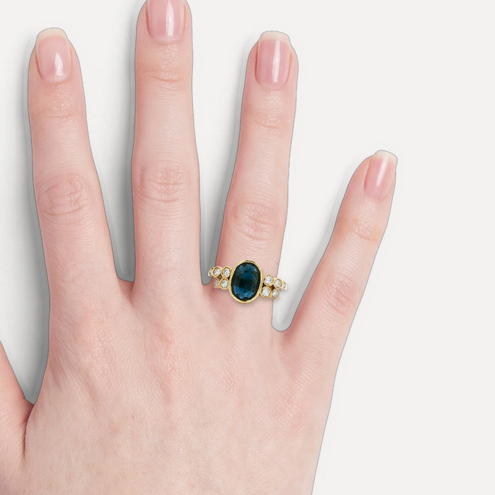 Oval Sapphire & Nearly Flawless Colorless Round Brilliant Cut Diamond Bezel-Set Ring (1 ⅖ ct. tw.) in 18k Yellow Gold shown on a hand (light skin tone)