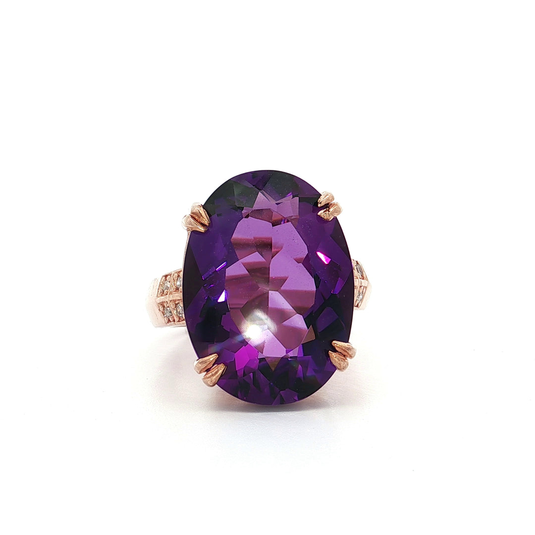 Oval amethyst gemstone ring with rose gold setting and diamond accents on white background