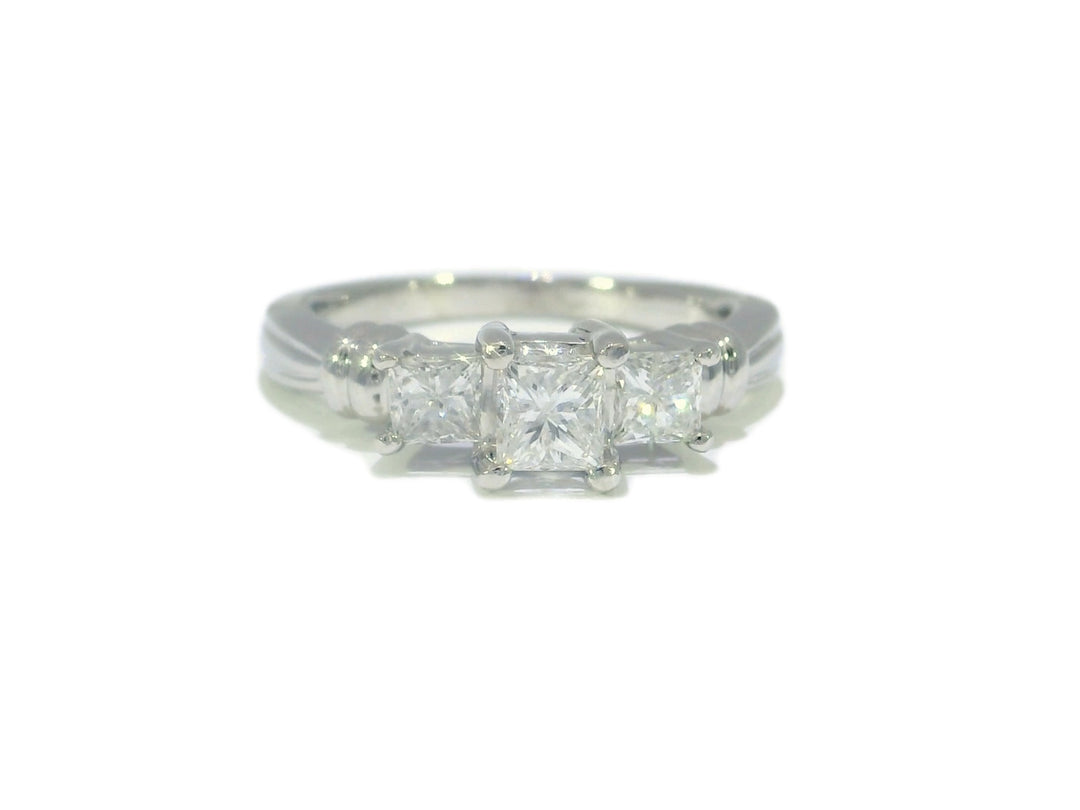 A colorless three-stone diamond engagement ring with a princess-cut center stone and two matching side stones, set in platinum.
