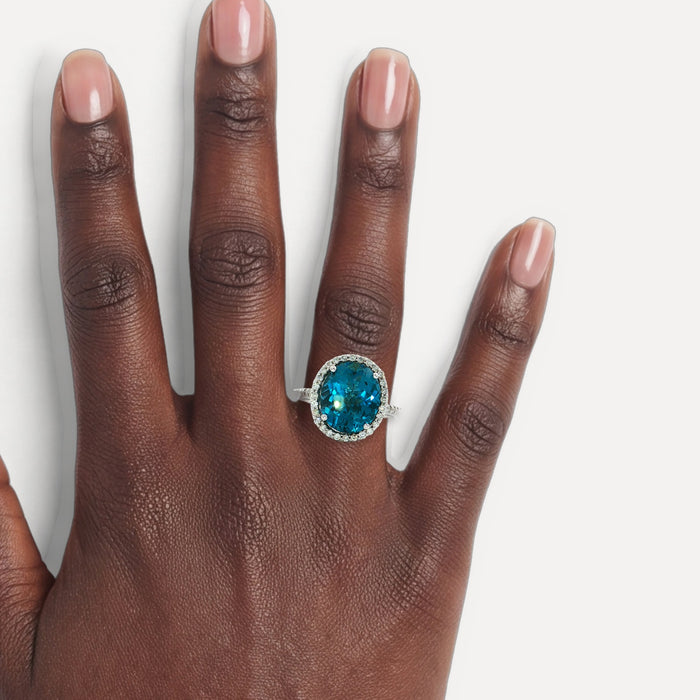 Oval-Shaped Deep London Blue Topaz & Colorless Diamond Halo Ring (7 ¼ ct. tw.) in 14k White Gold shown on a hand (deep skin tone)