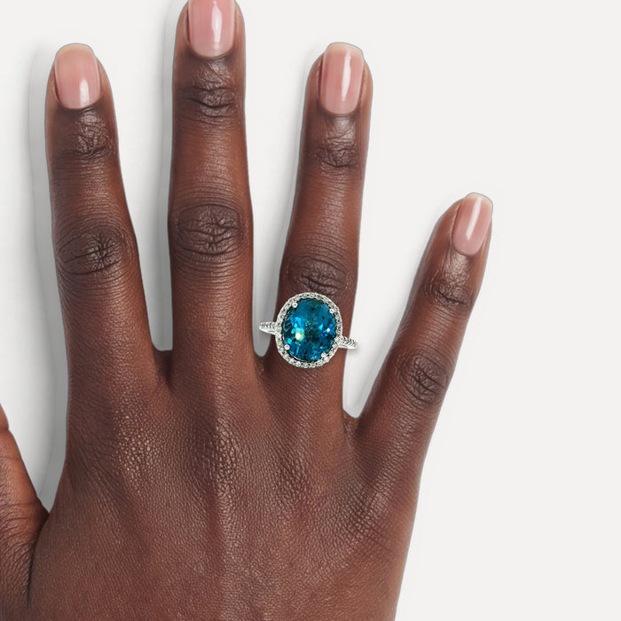 Oval-Shaped Deep London Blue Topaz & Colorless Diamond Halo Ring (7 ¼ ct. tw.) in 14k White Gold shown on a hand (deep skin tone)