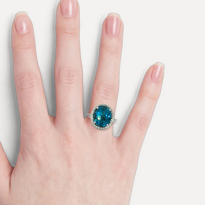 Oval-Shaped Deep London Blue Topaz & Colorless Diamond Halo Ring (7 ¼ ct. tw.) in 14k White Gold shown on a hand (light skin tone)