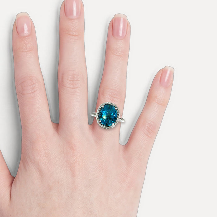 Oval-Shaped Deep London Blue Topaz & Colorless Diamond Halo Ring (7 ¼ ct. tw.) in 14k White Gold shown on a hand (light skin tone)