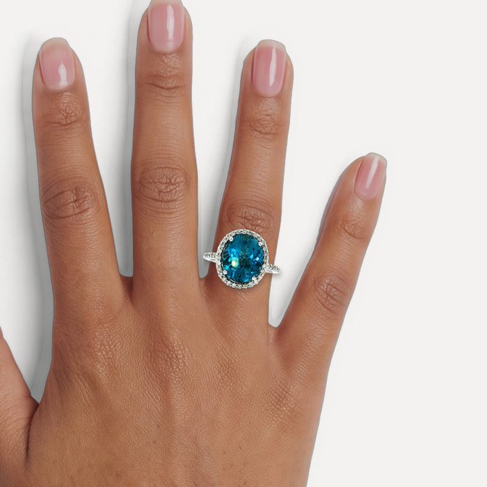 Oval-Shaped Deep London Blue Topaz & Colorless Diamond Halo Ring (7 ¼ ct. tw.) in 14k White Gold shown on a hand (medium deep skin tone)