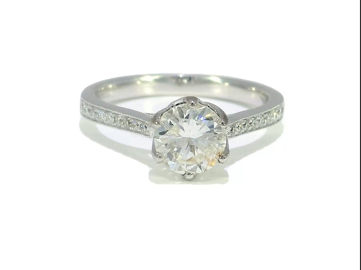A 1.35 CTW Round Brilliant Diamond Engagement Ring in 18KT White Gold with a solitaire center stone and pavé-set Diamonds on the band.
